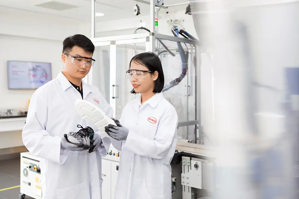 Two Henkel researchers in a laboratory analyze a shoe sole that has been bonded with innovative Henkel adhesives.