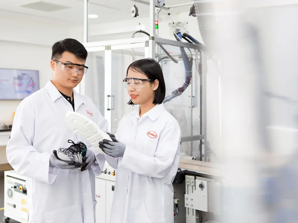 Two Henkel researchers in a laboratory analyze a shoe sole that has been bonded with innovative Henkel adhesives.