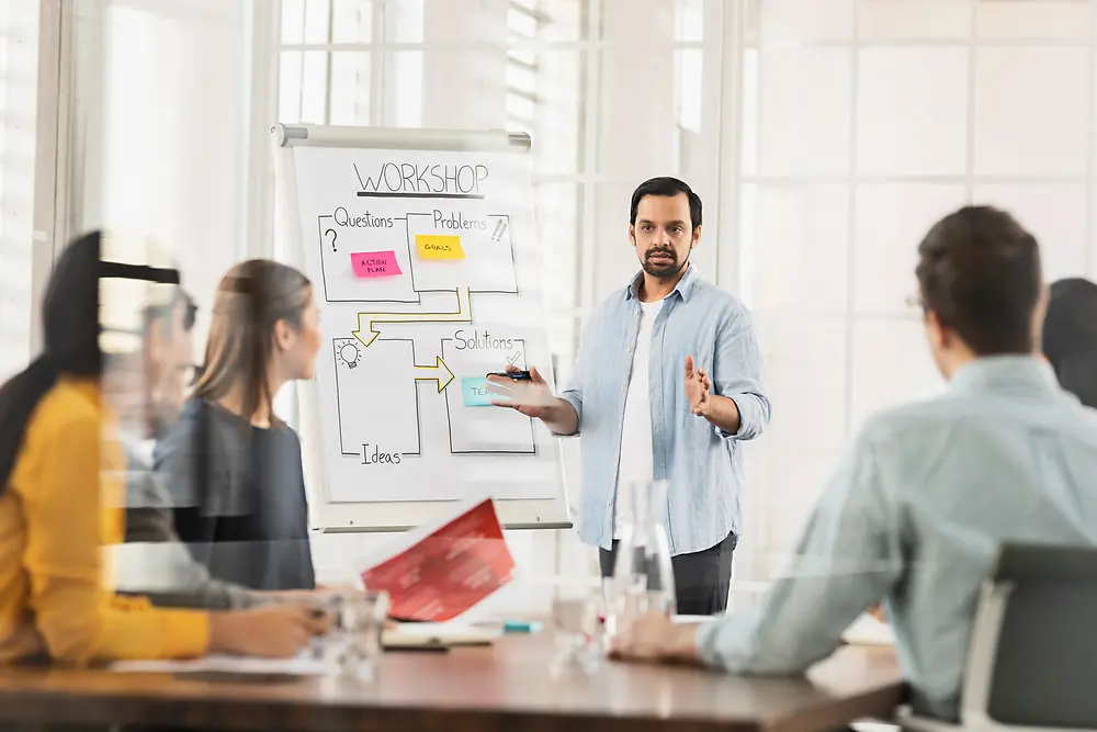 A man talks about solution-oriented thinking as a team in an agile project management workshop in front of four colleagues.