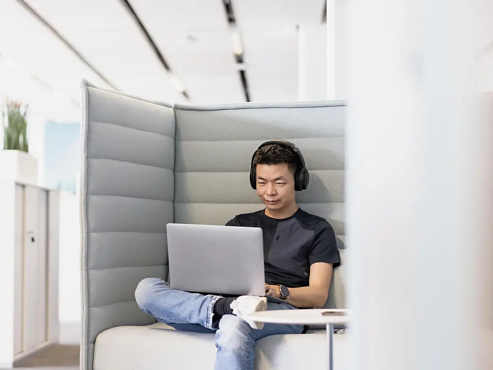 A Henkel employee with headphones works concentrated on his laptop.