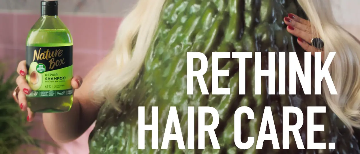 A Nature Box shampoo advertisement with the cowboy hat wearing blonde avocado