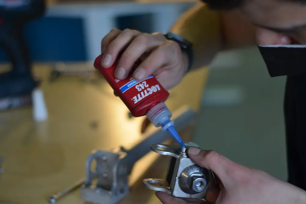 Eduardo puts glue on a metal part.