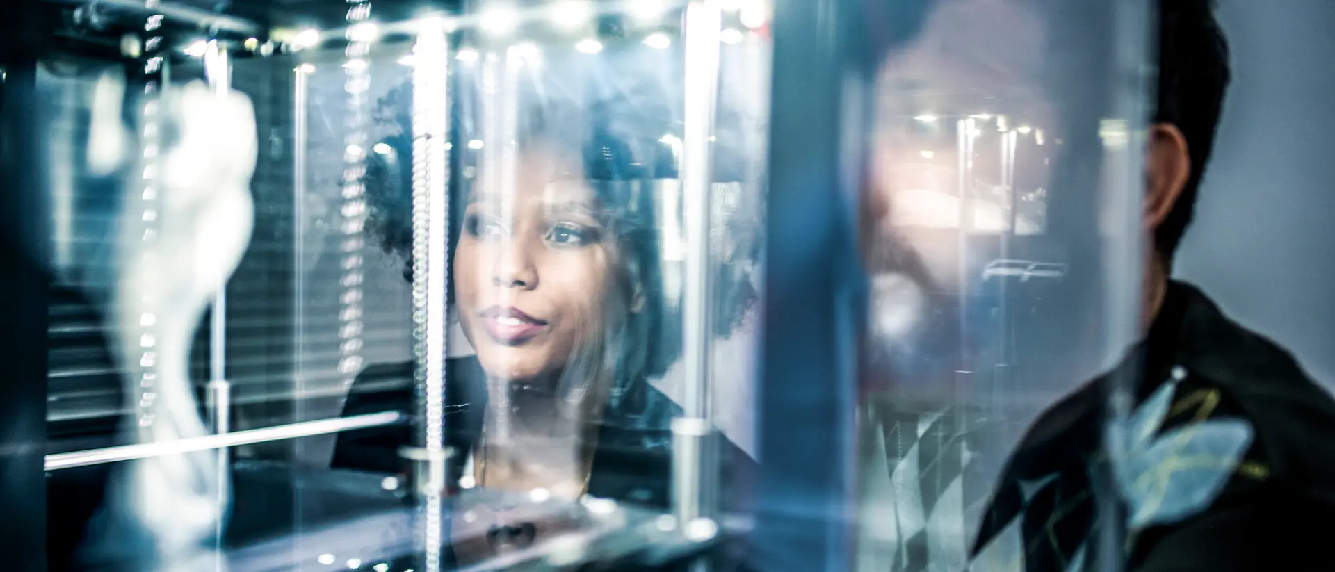 People in front of an illuminated display watching a 3D printing process.