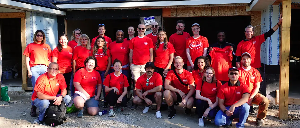 A group of people wearing red shirts in front of a house under construction