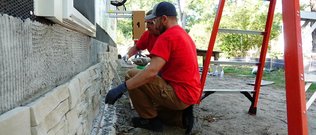 Two men repairing brick wall