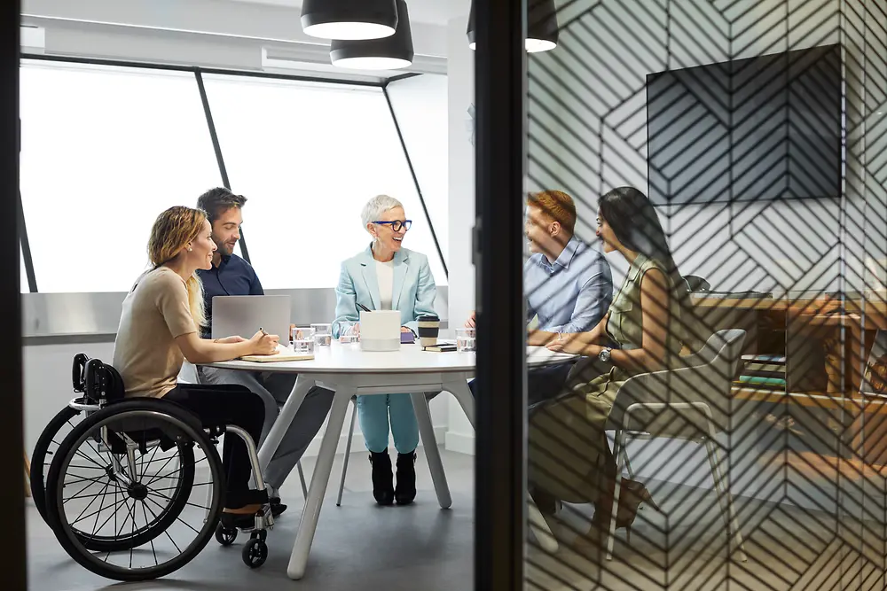 An Employee Resource Group sits together in a meeting room and exchanges. 