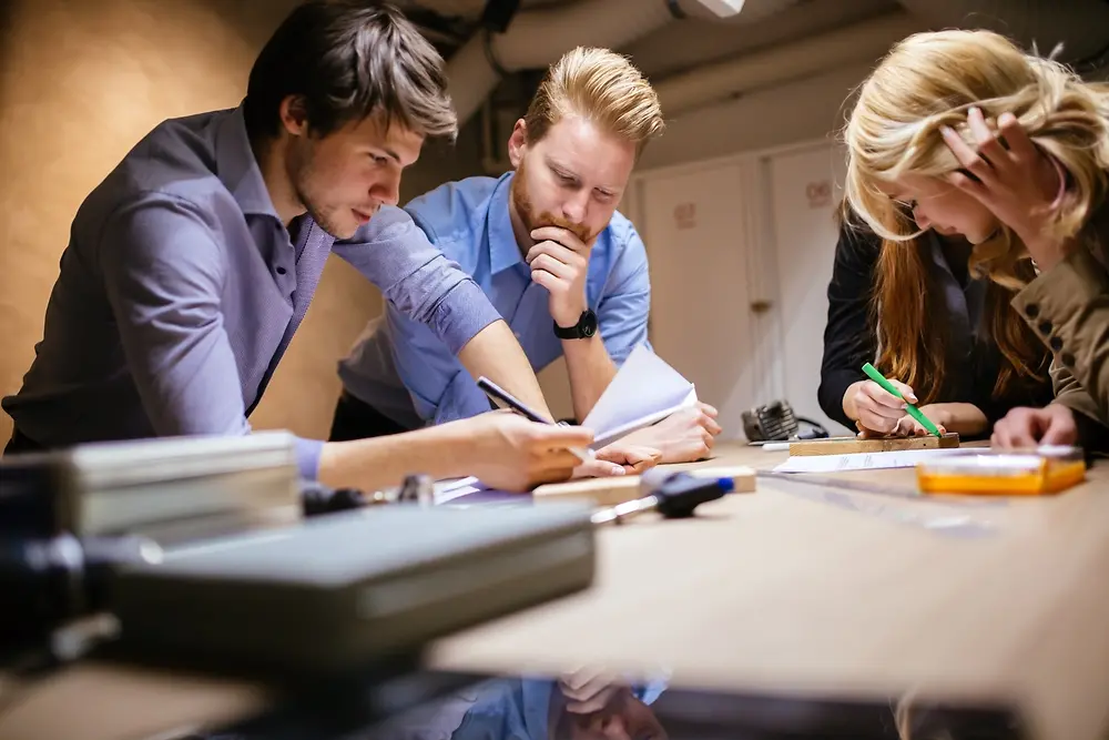 A group of 4 colleagues leaning on a table and checking some papers