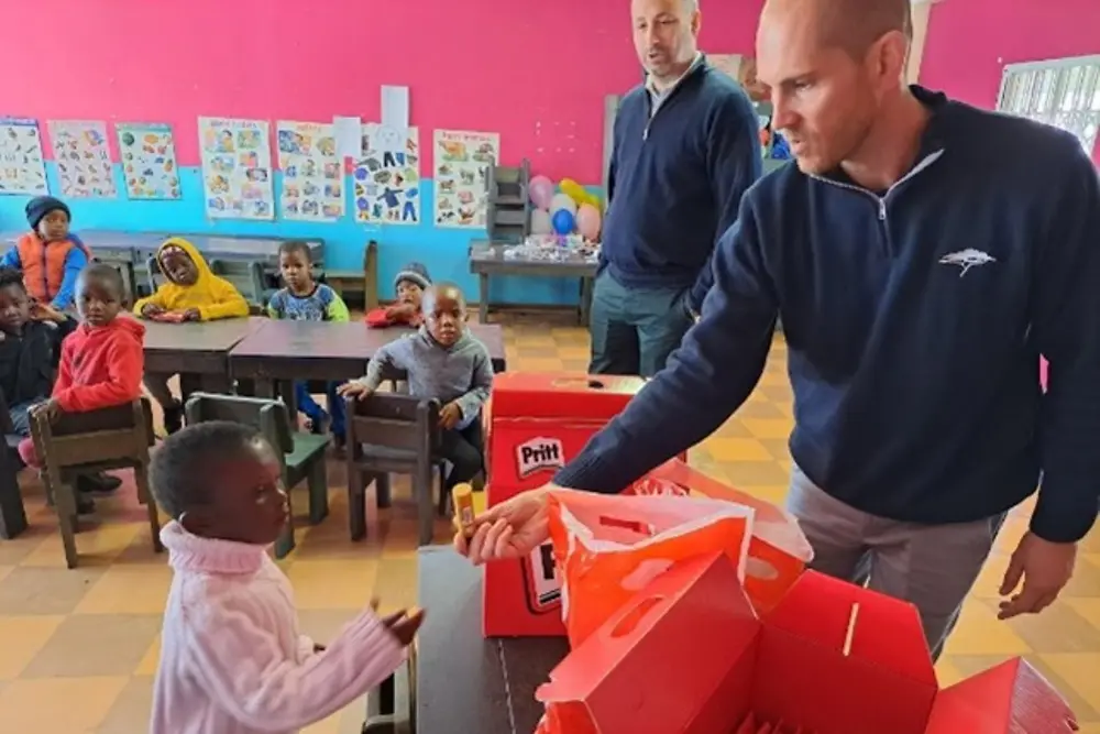 A Henkel volunteer hands a Pritt stick over to a child.