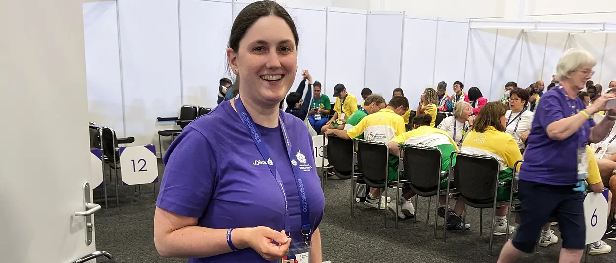 Katrin stands in one the preparation rooms for the Special Olympics athletes and smiles into the camera.