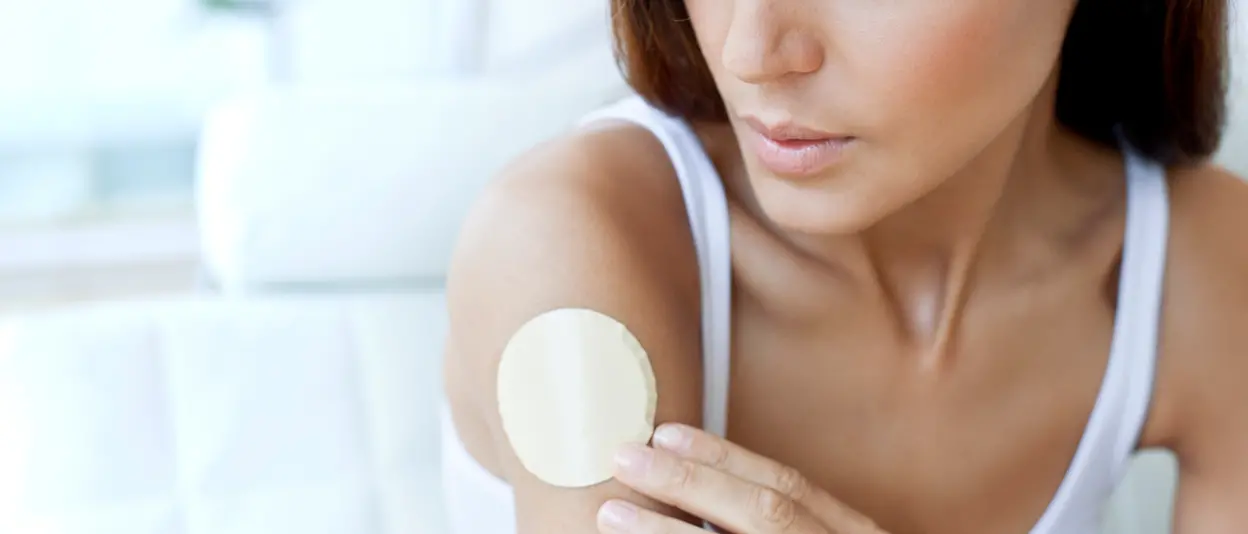 A young woman attaches a smart health patch to her right upper arm.