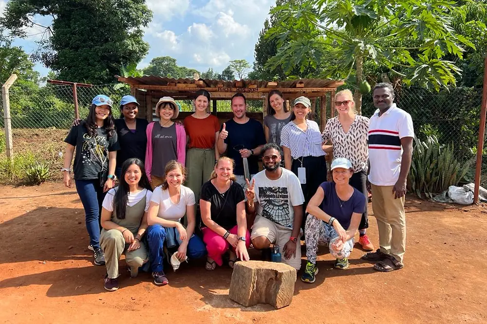 The participants of the team trip organized by Peace's Hope stand in front of the chicken coop they built together.