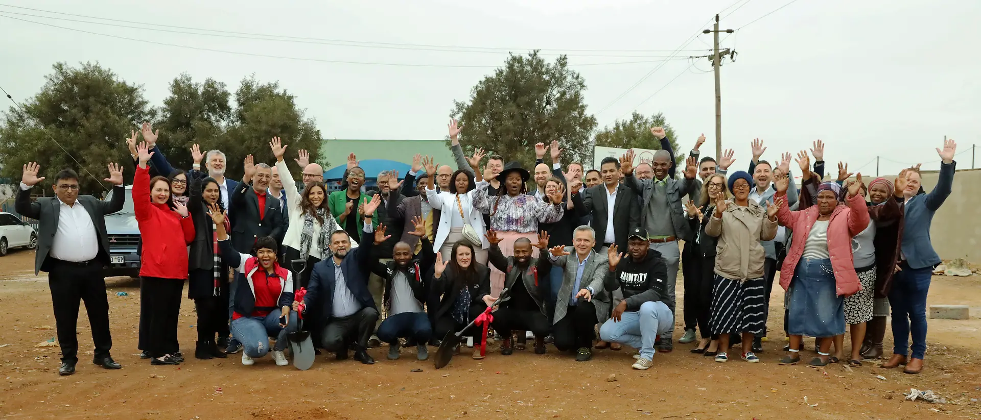 A large group cheers and raises their arms in the air.