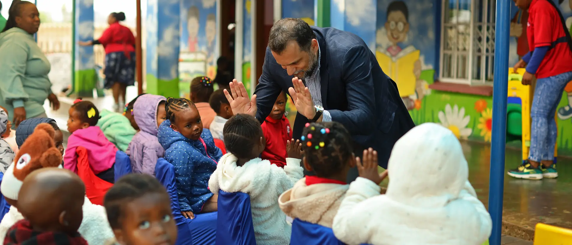 A group of small children high-five a volunteer.