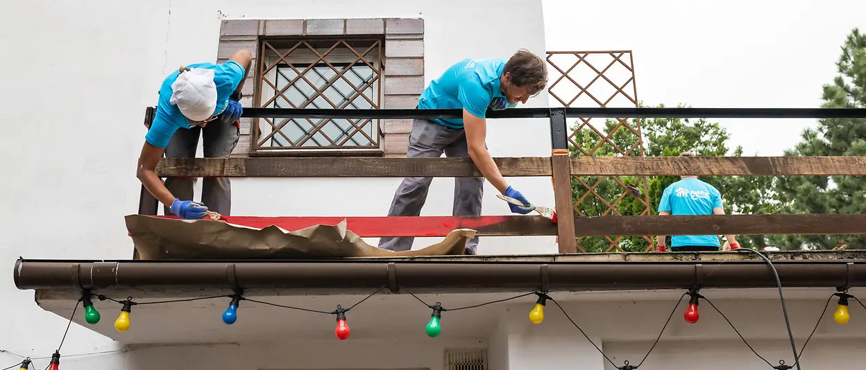 The volunteers build and paint a fence on the house’s balcony.