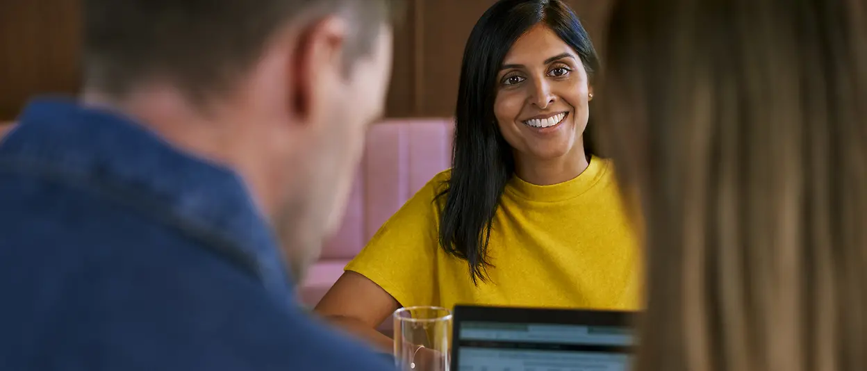 A woman smiling at the people sitting opposite her during a meeting.