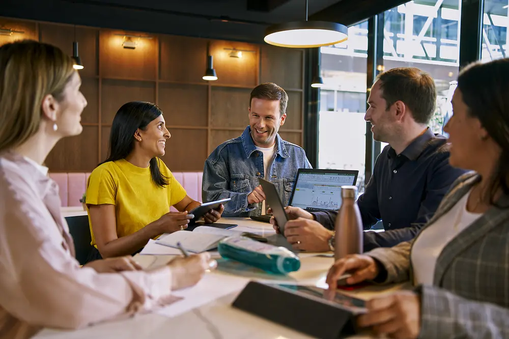 A group of people sitting at a table during a meeting. 