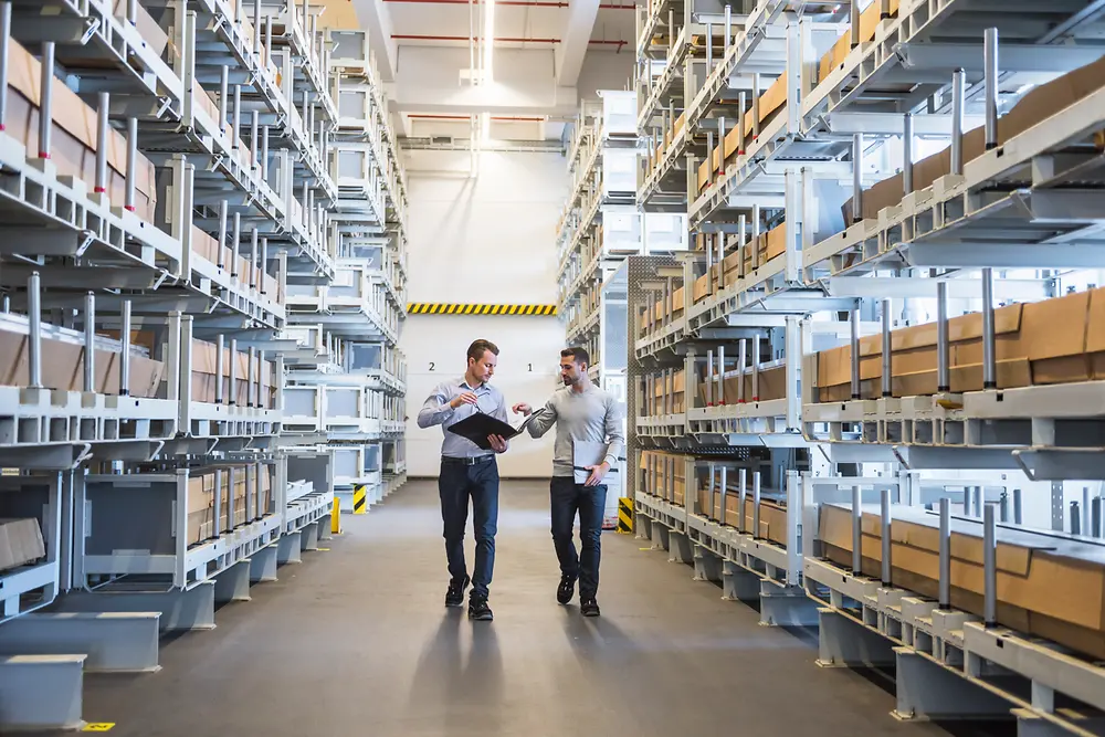 Two men are walking through a warehouse.