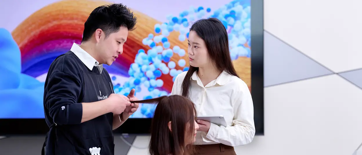 Two hair experts examine the strands of a customer's hair.