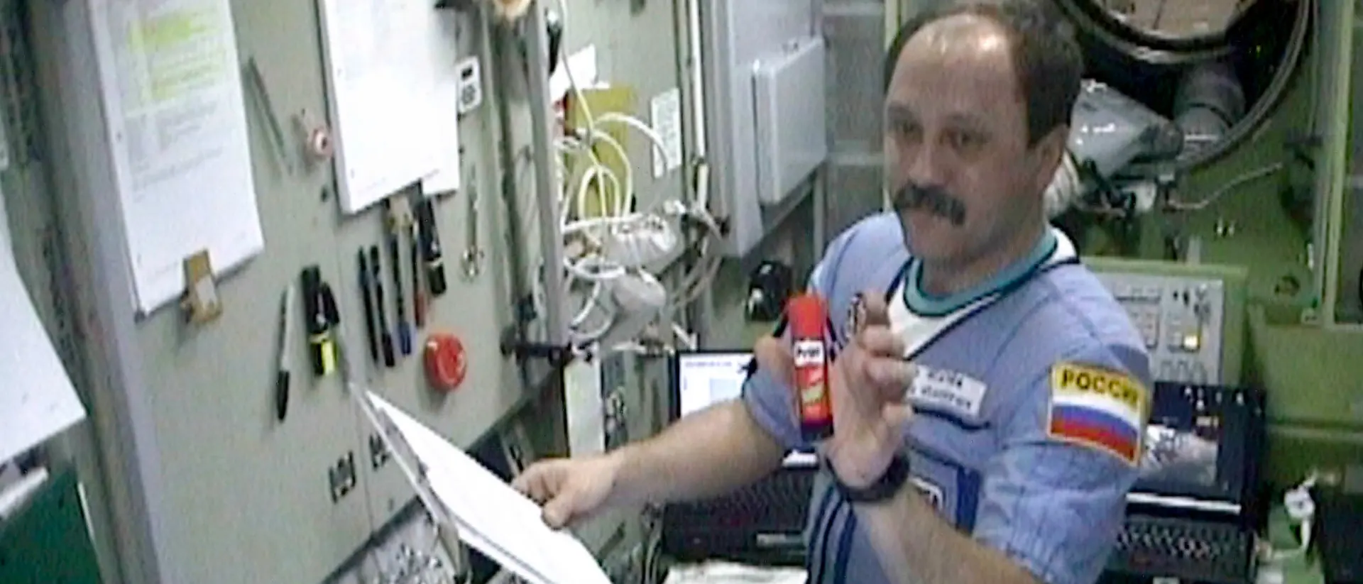 An astronaut on the International Space Station holds a Pritt glue stick in his hand.