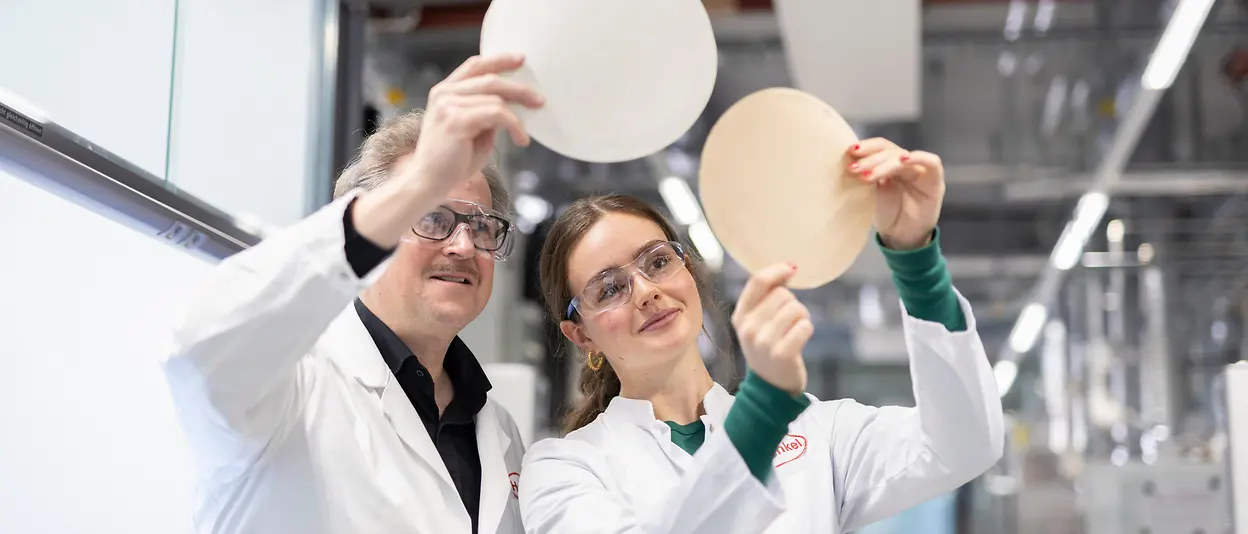 2) Two people in a lab comparing testing results of the paper recyclability