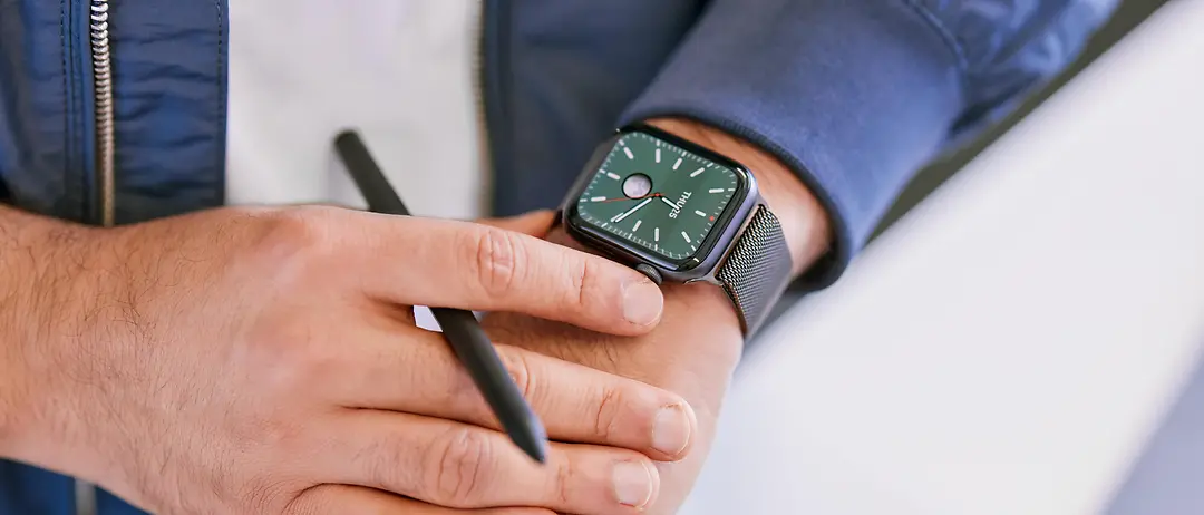 A close-up of hands with a smartwatch displaying the time on the left wrist.