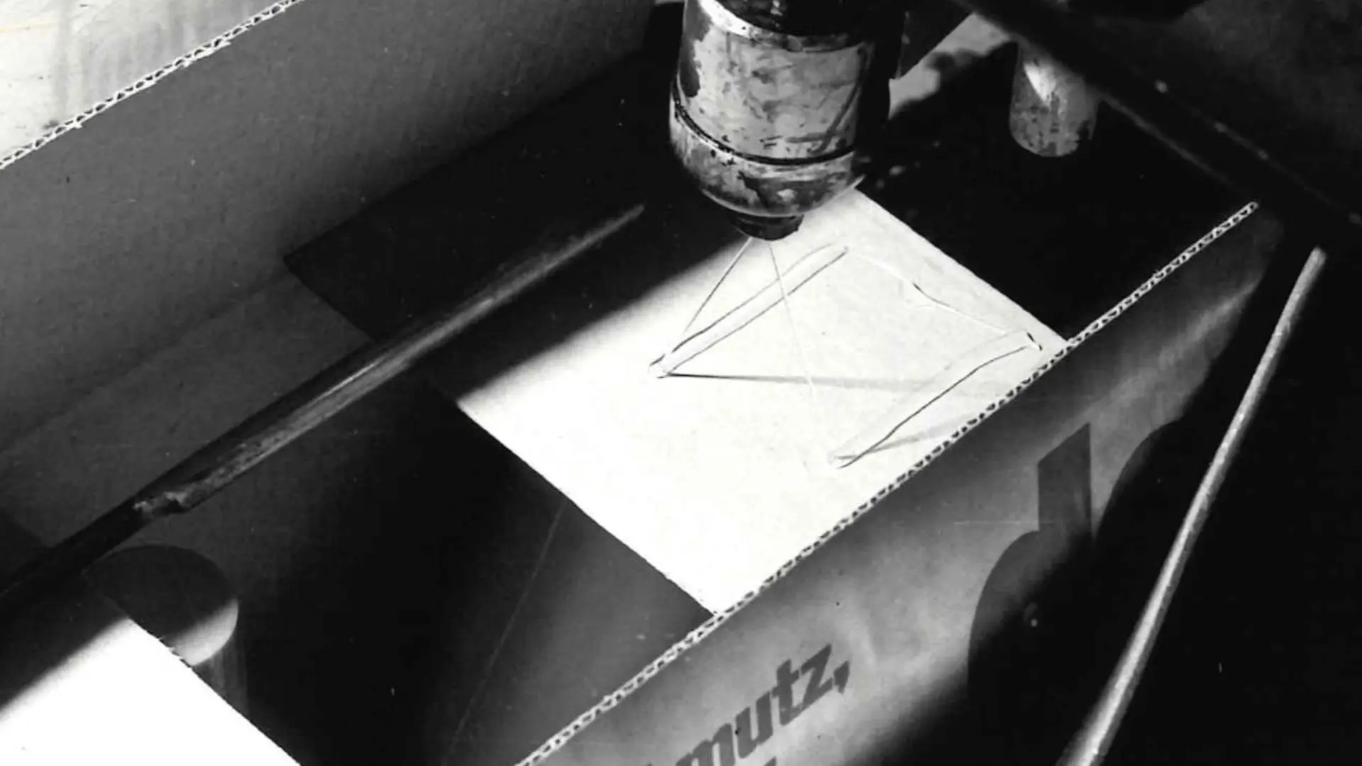 Technomelt hot melt adhesive is applied to a cardboard box by a spray head to seal it.