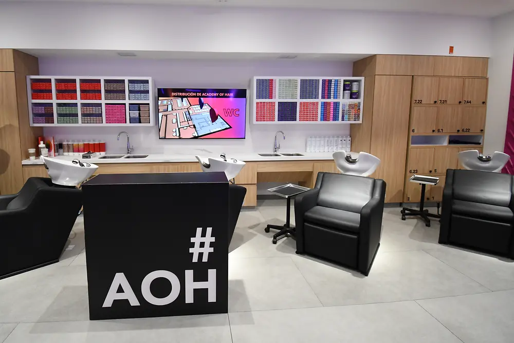 The image shows several wash stations and cabinets filled with various hairdressing products in a modern salon setting.